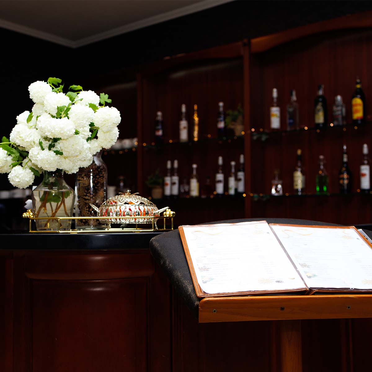 Барна стійка з меню, квітами та алкоголем на фоні у ресторані Solotvyno Resort
