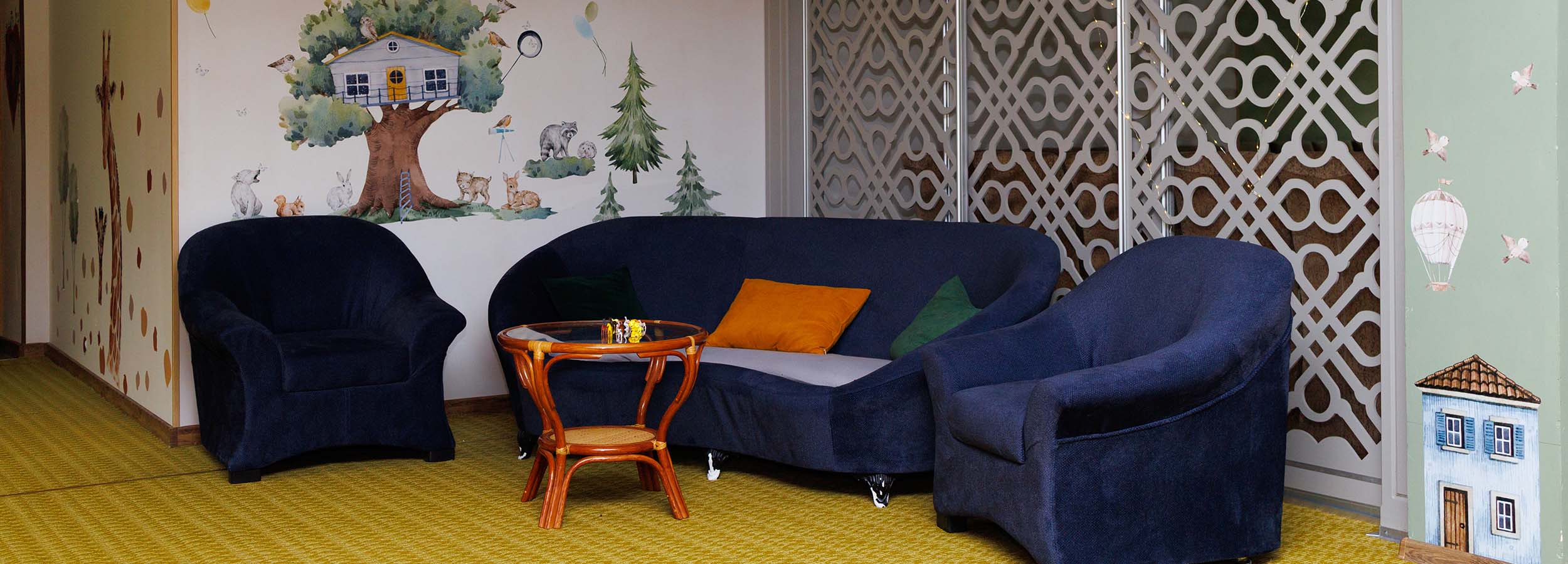 Дитяча зона з м’якими кріслами та настінним малюнком казкового дерева в Solotvyno Resort